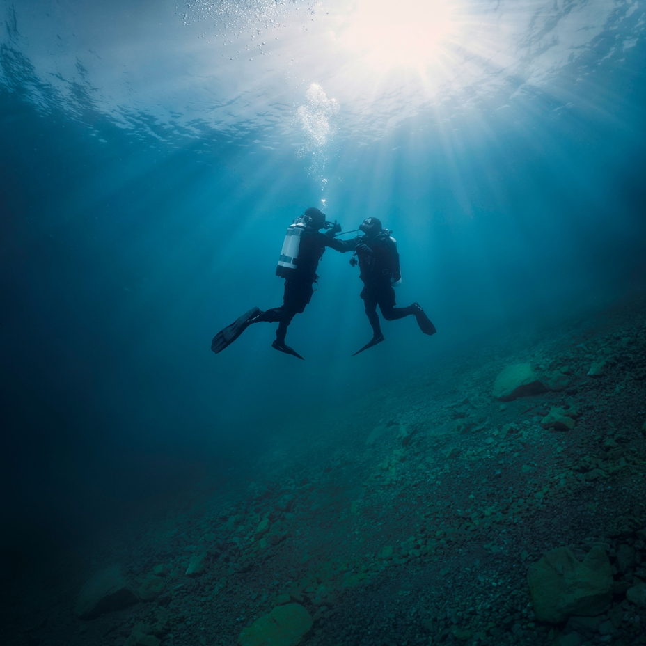 Undervandsscene: En dykker hjælper en anden dykker, som har problemer med luftforsyningen.